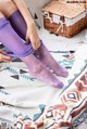 A woman is tying up her purple stockings on a blanket.