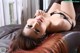 A woman laying on top of a brown leather couch.