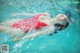 A woman in a red bathing suit floating in a pool.