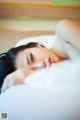 A woman laying on a bed with her eyes closed.