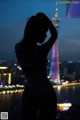 A woman standing in front of a city skyline at night.