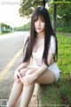 A young woman sitting on the side of a road.