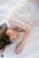 A woman laying on a bed in a white lingerie.