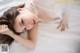 A woman laying on a bed in a white lingerie.