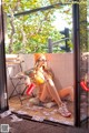 A woman in a yellow bikini sitting on a window sill.