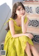 A woman in a yellow dress sitting on some steps.