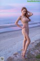 A woman in a beige dress standing on a beach.