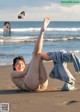 A woman laying on the beach with her legs up in the air.