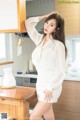 a woman in a white dress standing in a kitchen