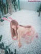 A woman in a pink bunny costume crouching on a bed of white pebbles.