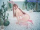 A woman in a pink bunny costume crouching on a bed of white pebbles.