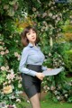 A woman in a blue shirt and black skirt holding a clipboard.