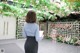 A woman standing in front of a floral wall holding a clipboard.