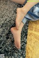 A woman sitting on a rug with her bare feet.