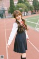 A young woman in a school uniform standing on a track.