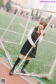 A woman in a school uniform standing next to a soccer goal.