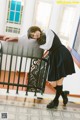 A woman in a school uniform leaning on a railing.