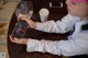 A young boy sitting at a table with a cup of coffee and a phone.