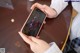 A person sitting at a table holding a cell phone.