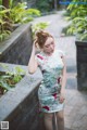 A woman in a floral dress standing on a stone wall.