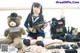 A woman in a sailor outfit holding a rifle next to a teddy bear.