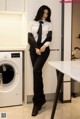 A woman in a white shirt and black tie standing next to a washing machine.