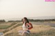 A woman sitting on the side of a road with a backpack.