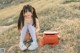 A young woman sitting on the ground with a backpack.