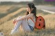 A young woman sitting in a field with a backpack.