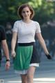 A woman in a white shirt and green skirt walking down the street.