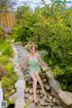 A woman in a green dress sitting on a stone path.