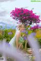 A woman in a green dress standing in a field of flowers.