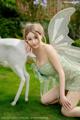 A woman in a fairy costume posing next to a white deer.