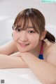 A young woman in a bathtub smiling at the camera.