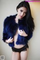 A woman in a blue fur coat posing for a picture.