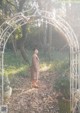 A woman standing in front of an archway in the woods.