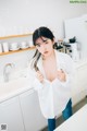 A woman standing in a kitchen next to a sink.