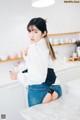 A woman sitting on top of a counter in a kitchen.
