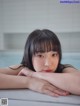 A woman laying on the edge of a bathtub with her hand on her chin.