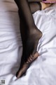 A woman in black stockings is laying on a bed.