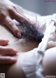 A close up of a woman's hand touching her hairy breasts.