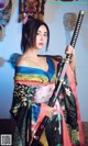 A woman in a kimono holding a samurai sword.