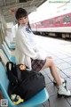 A woman sitting on a bench at a train station.