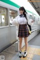 A woman in a school uniform standing next to a train.