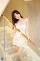 A woman in a white dress is posing on a staircase.