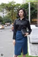 A woman in a black shirt and blue skirt posing for a picture.