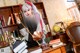 A woman dressed as a nun holding a broom in front of a desk.