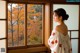 A woman in a kimono looking out a window.