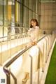 A woman in a white coat is standing on a railing.