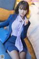 A woman in a blue suit sitting on a bed.